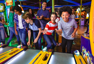 Youth and families enthusiastically playing interactive arcade games