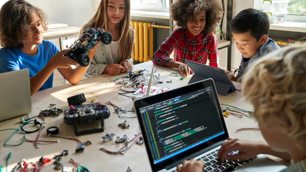 Youth collaborating on STEM robotics and coding around a shared workshop table